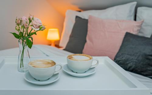 two cups of coffee and a vase with flowers on a table at Rodinný penzion Sobáčov in Sobačov