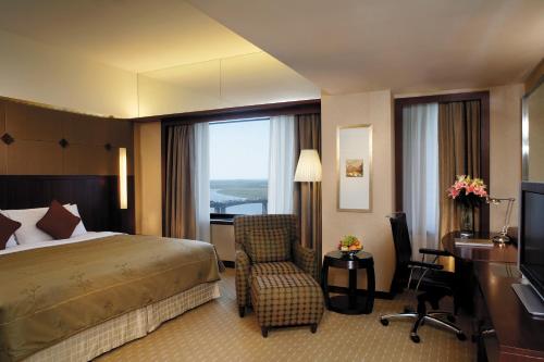 a hotel room with a bed and a desk and a chair at Shangri-La Harbin in Harbin