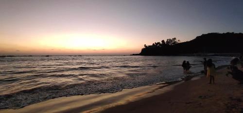 a group of people standing on the beach at sunset at Baga View Inn in Baga