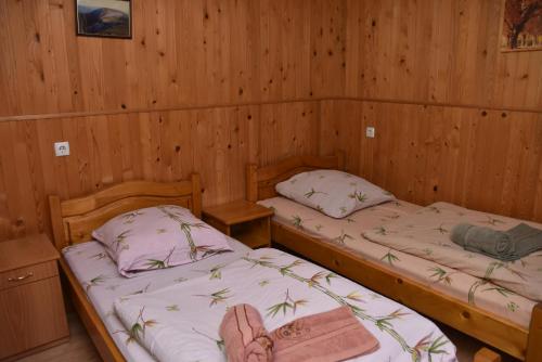 two beds in a room with wooden walls at Guest House Mandrivnyi Rooms&Apartments in Yasinya