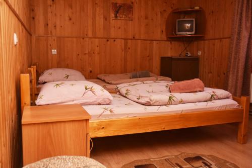 two beds in a wooden room with a tv on the wall at Guest House Mandrivnyi Rooms&Apartments in Yasinya