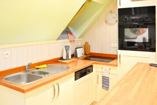 une cuisine avec un évier et une cuisinière dans l'établissement Maison charmante à Plomelin avec jardin., à Plomelin