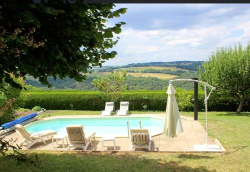 a swimming pool with chairs and an umbrella at Villa de 6 chambres avec piscine privee jardin clos et wifi a Mur de Barrez in Mur-de-Barrez