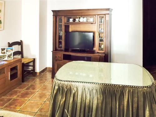 sala de estar con TV y mesa en 2 bedrooms house with city view and furnished balcony at Setenil de las Bodegas, en Setenil