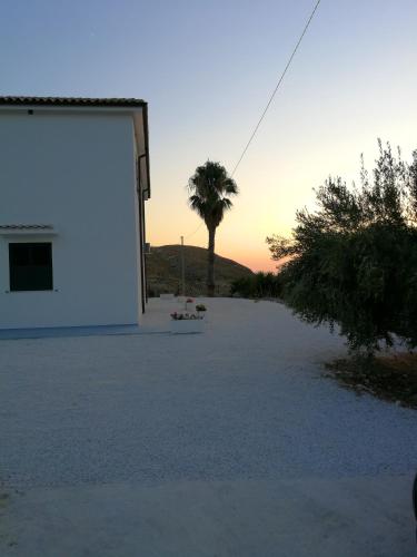 a building with a palm tree in the sunset at Charming apartment in Montallegro with sea view in Montallegro