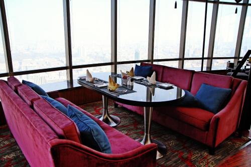 a restaurant with red couches and a table in front of a window at Enlux Hotel in Jinan