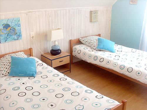 CléderにあるMaison de 4 chambres a Cleder a 500 m de la plage avec jardin clos et wifiのベッド2台、テーブル(ランプ付)が備わる客室です。