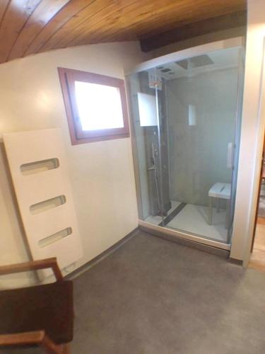 une salle de bain avec douche et porte vitrée dans l'établissement Chalet chaleureux à Saint-Chaffrey avec vue montagne et cheminée, à Saint-Chaffrey