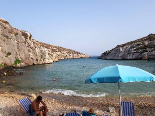 a couple of people sitting on a beach with an umbrella at Charming House in Ix - Xewkija with Terrace and Barbecue in Xewkija