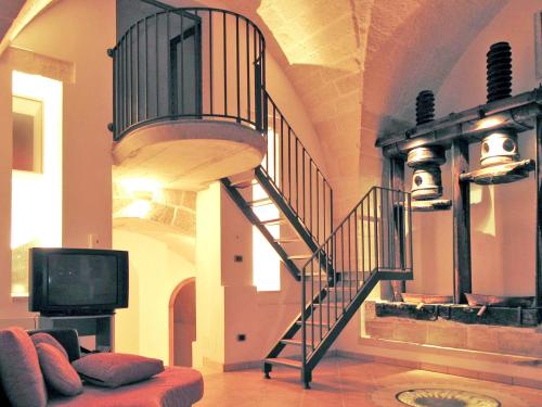 a living room with a spiral staircase and a tv at 3 bedrooms house with enclosed garden and wifi at Surano 7 km away from the beach in Surano