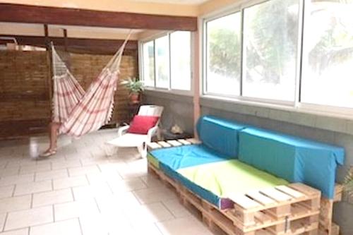 a living room with a blue couch and a hammock at Maison charmante vue sur mer à La Trinité, 2 chambres. in La Trinité