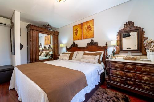 a bedroom with a large bed with a dresser and a mirror at Luxurious House in Braga with Pool in Barreiros