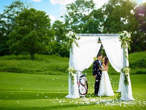 a bride and groom standing under a wedding arch at Mission Hills Hotel Resorts Dongguan in Dongguan