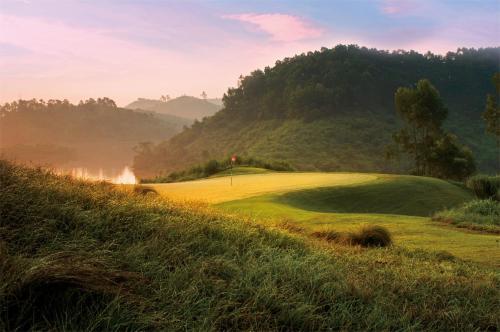 a golf course in the hills with a green at Mission Hills Hotel Resorts Dongguan in Dongguan