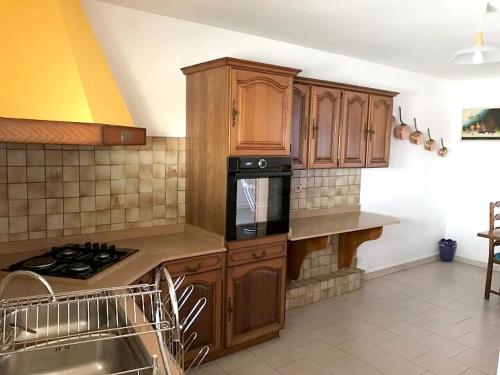 a kitchen with wooden cabinets and a stove at Appartement lumineux aux Trois-Îlets in Les Trois-Îlets