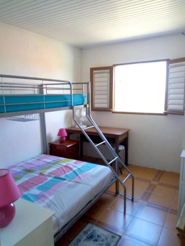 a bedroom with a bunk bed with a desk and a window at Maison de charme vue mer et montagne au François in Le François