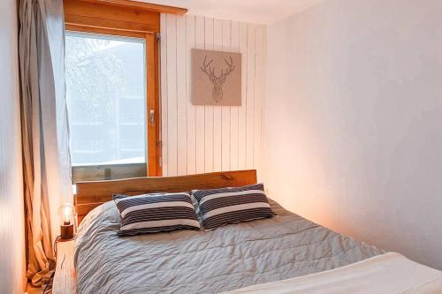 a bedroom with a bed with two pillows and a window at Anzère - Appartement 2 pièces au pied du télécabine in Anzère