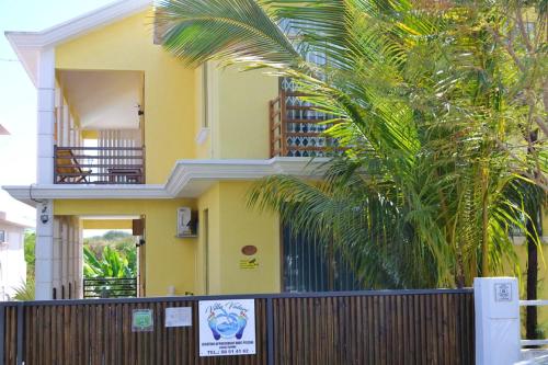 a yellow house with a fence and palm trees at Modern apartment in Pereybère with pool view, 50 m² in Pereybere