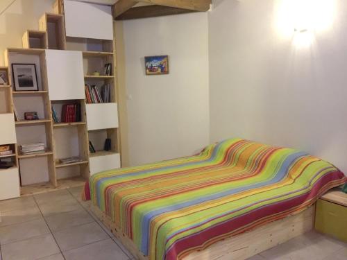 Una cama con una manta de rayas de colores en una habitación en Maison de 2 chambres avec piscine privee jardin amenage et wifi a Saint Joseph a 6 km de la plage, en Saint-Joseph