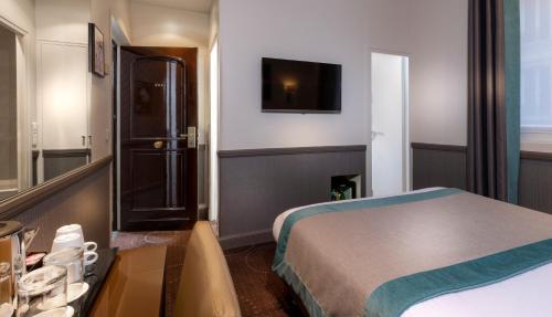 a hotel room with a bed and a flat screen tv at Elysées Ceramic in Paris