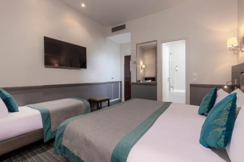 a hotel room with two beds and a flat screen tv at Elysées Ceramic in Paris