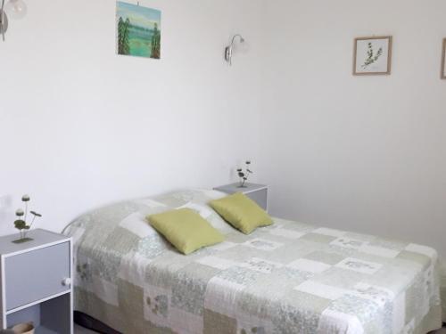 ein weißes Schlafzimmer mit einem Bett mit zwei gelben Kissen in der Unterkunft Maison de 2 chambres avec jardin clos et wifi a Pujaut in Pujaut