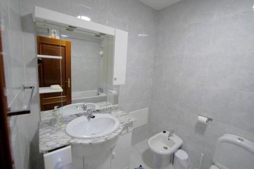 a bathroom with a sink and a toilet and a mirror at 4 bedrooms house with city view balcony and wifi at Santa Maria da Feira in Aveiro