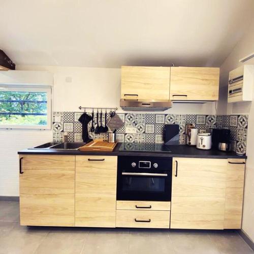 La cuisine est équipée d'armoires en bois et d'un four noir. dans l'établissement Maison cosy à Chouzy sur Cisse avec jardin, à Chouzy-sur-Cisse