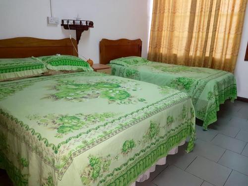 two beds in a room with green comforters at 3 bedrooms appartement with shared pool and furnished terrace at Trou aux Biches in Trou aux Biches
