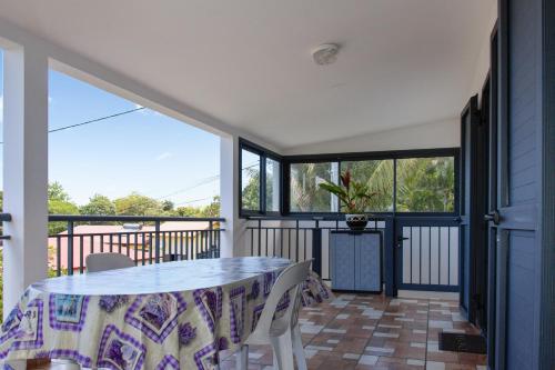 a dining room with a table and chairs on a balcony at Maison confortable avec vue sur mer à Sainte-Rose + jardin in Sainte-Rose
