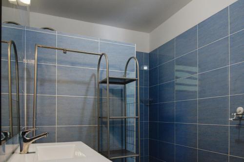 a bathroom with a sink and a shower with blue tiles at Maison confortable avec vue sur mer à Sainte-Rose + jardin in Sainte-Rose