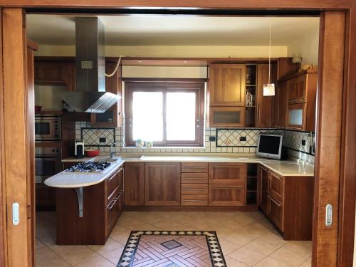 une grande cuisine avec des placards en bois et une fenêtre dans l'établissement 3 bedrooms appartement with city view and balcony at Cosenza, à Cosenza