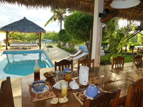 un tavolo con cibo e bevande accanto a una piscina di 2 bedrooms bungalow with sea view shared pool and enclosed garden at Andilana ad Andilana