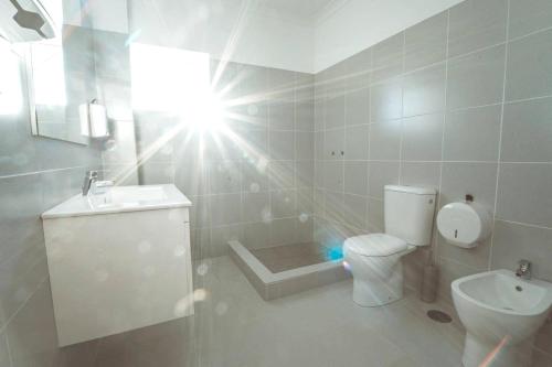 a white bathroom with a toilet and a sink at 2 bedrooms appartement with shared pool enclosed garden and wifi at Estoi in Estói