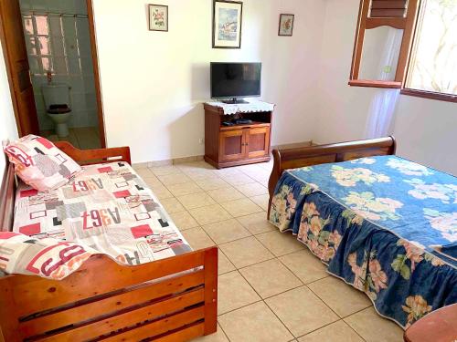a bedroom with two beds and a television in it at Appartement moderne à Sainte-Anne avec jacuzzi - 48 m². in Sainte-Anne