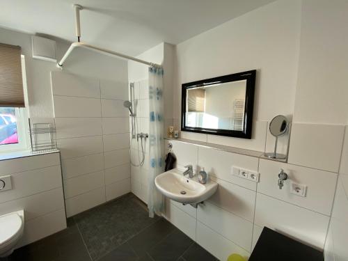 a white bathroom with a sink and a mirror at Ferienwohnung Zum Kiessee in Schwarmstedt