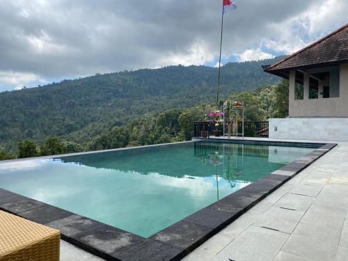 a swimming pool with a mountain in the background at Munduk Sari Resort in Munduk