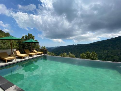 a swimming pool with chairs and a mountain view at Munduk Sari Resort in Munduk
