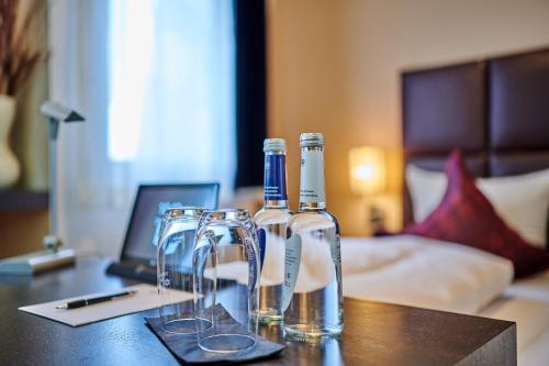 two bottles of wine sitting on a table with glasses at Genusshotel Wenisch in Straubing