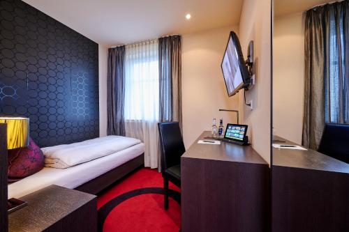 a hotel room with a bed and a desk with a laptop at Genusshotel Wenisch in Straubing