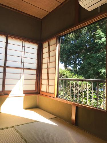 a room with a window with a view of a tree at Guesthouse Nishihara in Atami