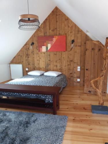uma cama num quarto com uma parede de madeira em La Petite Roupie em Bretteville