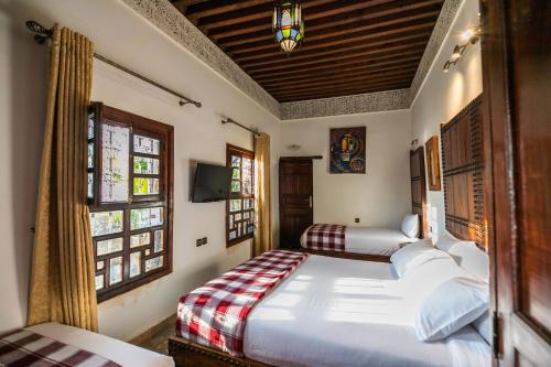a bedroom with two beds in a room with windows at Riad Fes Aicha & SPA in Fès