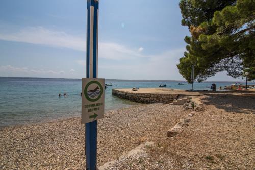 a sign on a pole on a beach near the water at Camp Sibuljina in Šibuljina