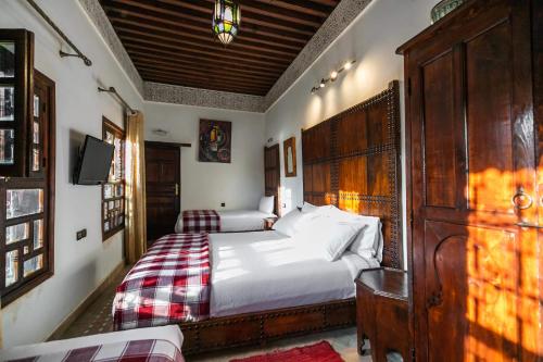 a bedroom with two beds and a wooden headboard at Riad Fes Aicha & SPA in Fès