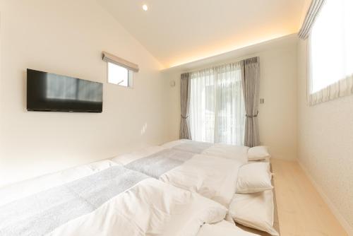 a white bedroom with a large bed and a tv at The Guest Villa 箱根湯本 V-II in Hakone