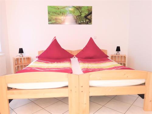 sypialnia z drewnianym łóżkiem z czerwonymi poduszkami w obiekcie Citywohnung am Rannischen Platz II w mieście Halle (Saale)