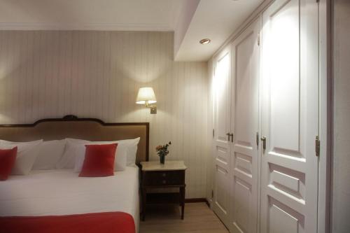 a bedroom with a bed with white sheets and red pillows at Ramada by Wyndham Buenos Aires Centro in Buenos Aires