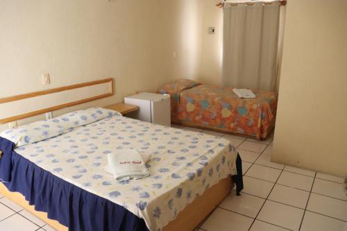 Un dormitorio pequeño con una cama y un refrigerador. en Tahen Hotel, en Santa Quitéria