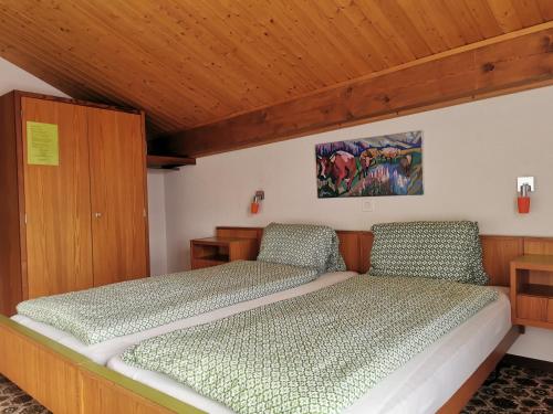 a bed in a bedroom with a wooden ceiling at Hotel Derby in Fiesch